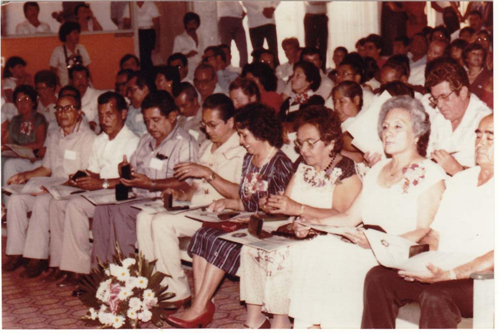 Hombres y mujeres en auditorio.