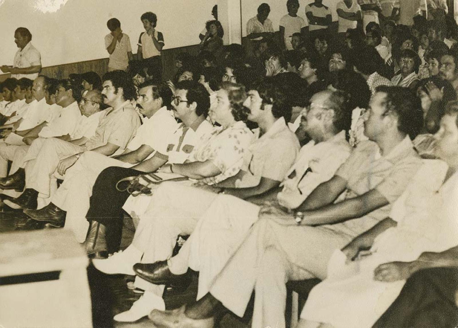 Hombres y mujeres en auditorio.