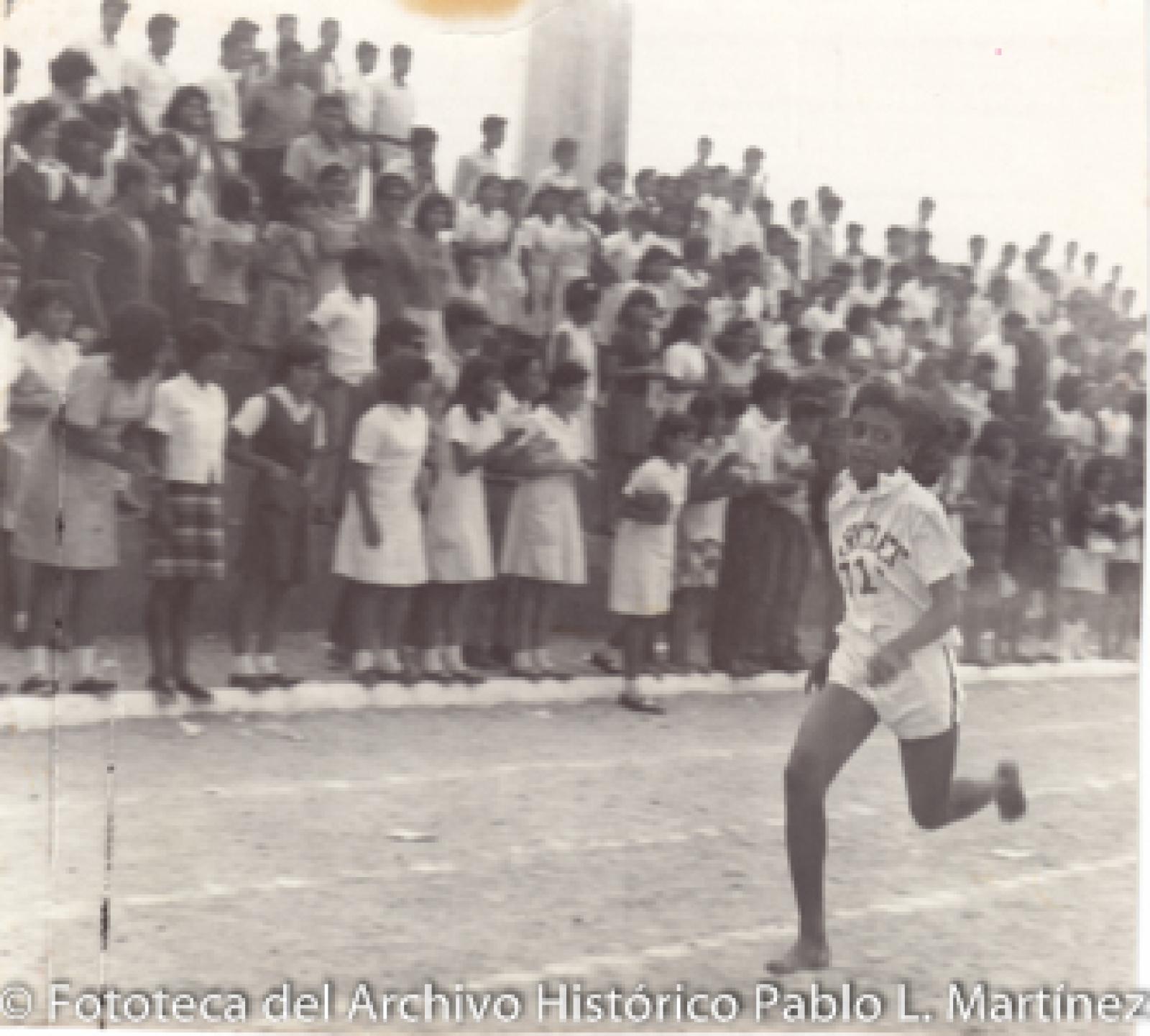Joven en competencia de carreras frente a público.