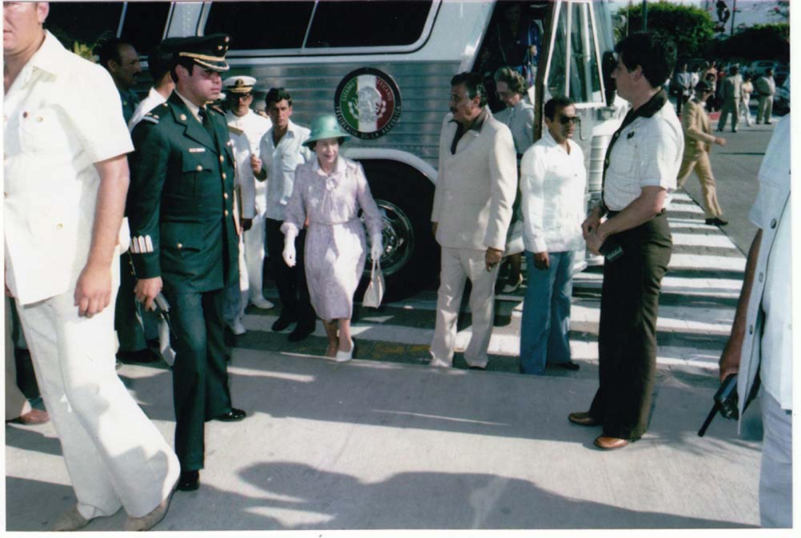 La reina Isabel II y comitiva, al lado de autobús oficial.