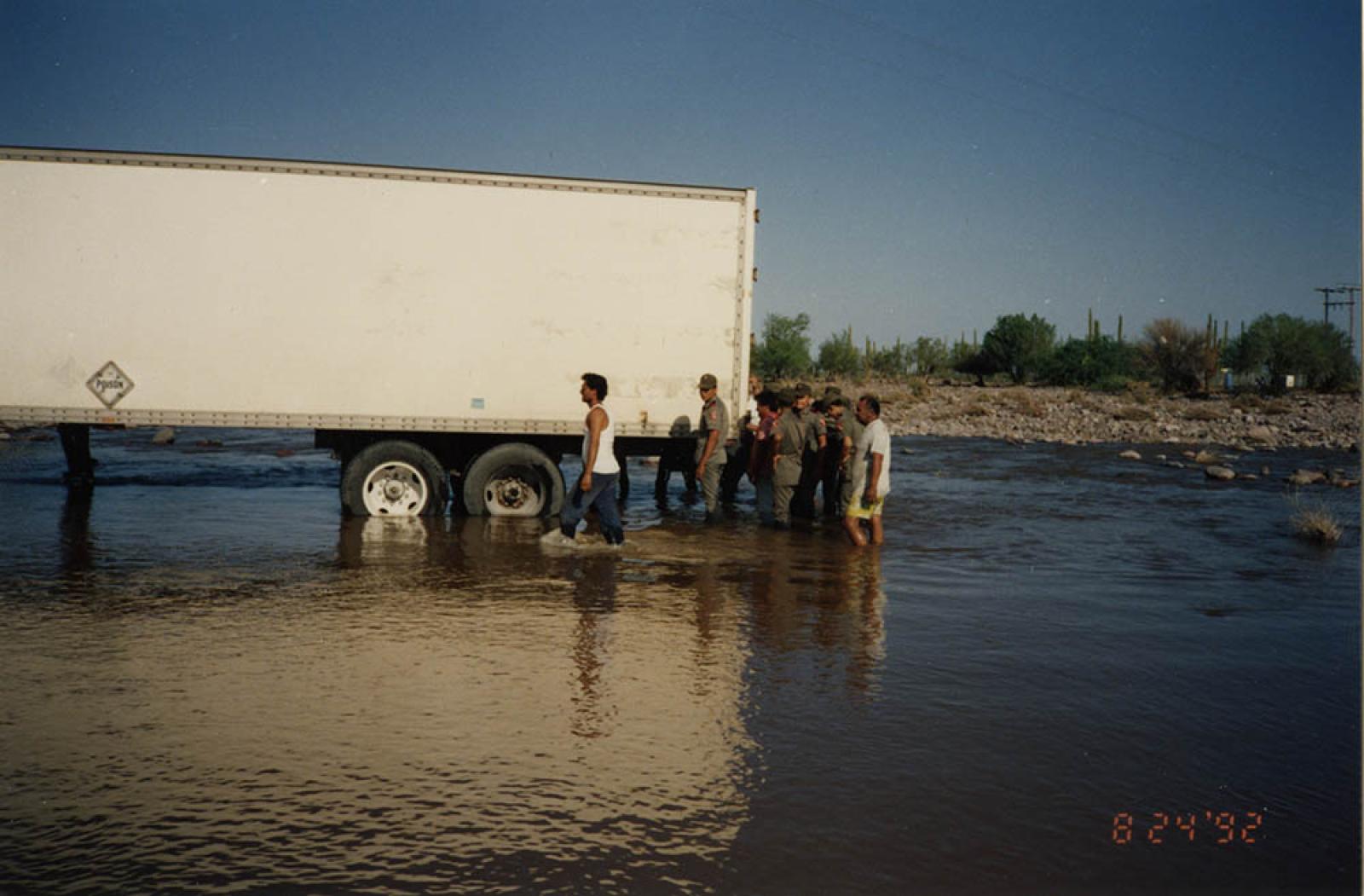 Militares apoyando para sacar un tráiler atascado en un vado.