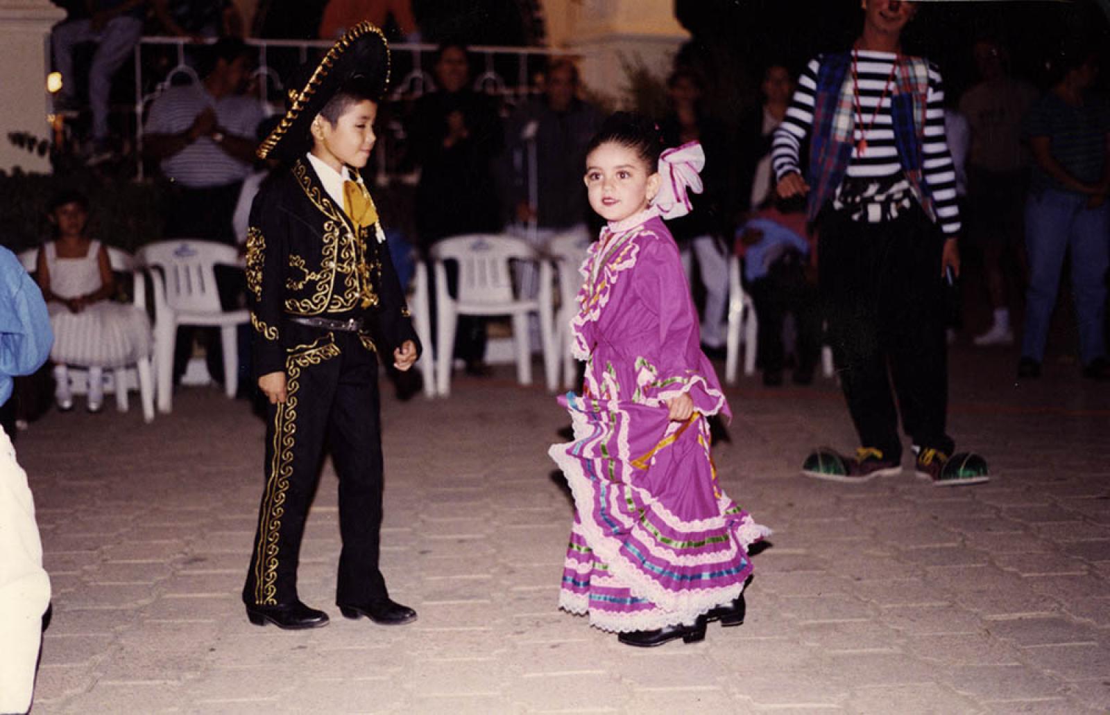 Niño y niña ejecutan danza folklórica.