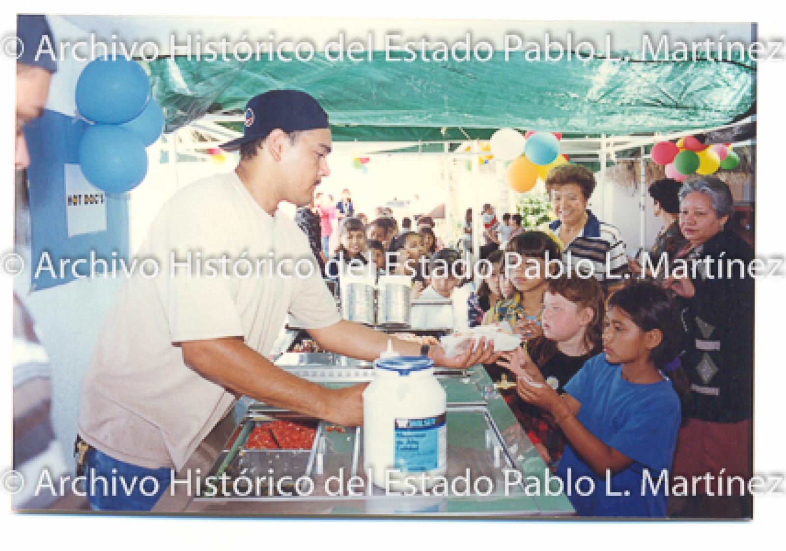 Niños en fiesta les preparan hot dogs.