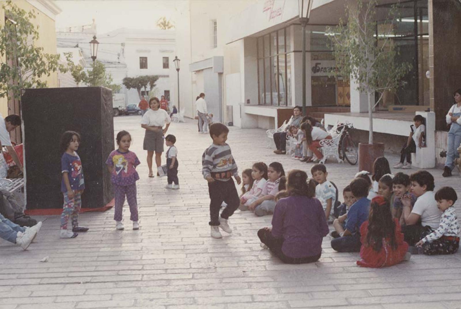 Niños, hombres y mujeres en el callejón de los artesanos.