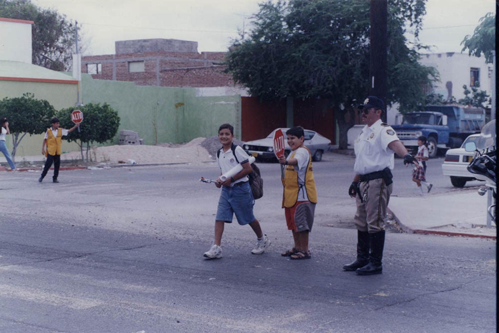 Policía y niños moderan tránsito vial.