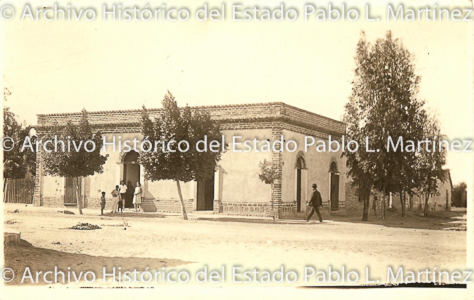 Señora y niños en la entrada de una casa rodeada de arboles y un señor y niña que caminan sobre la banqueta.